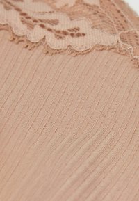 Roze stof met verticale ribbelstructuur, met een kantafwerking aan de bovenkant met gegolfde randen en delicate bloempatronen.