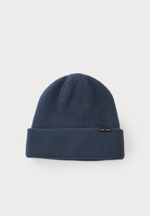 Navy knit beanie with ribbed texture and a folded cuff. Features a small black logo tag on the side. Soft material, round top design.