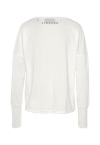 White long-sleeve shirt with a relaxed fit and dropped shoulders; features subtle brand logo in gray near the neckline; soft fabric texture.