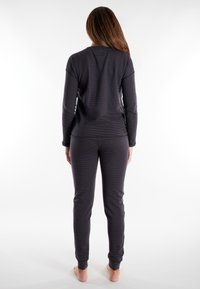 Top gris de manga larga con rayas sutiles, combinado con pantalones ajustados a juego. Ambos tienen puños acanalados y un ajuste relajado.