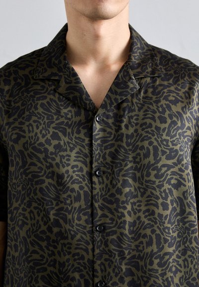Camicia a maniche corte con un motivo animalier verde e nero, realizzata in un tessuto liscio, con colletto a camicia e chiusura con bottoni neri.