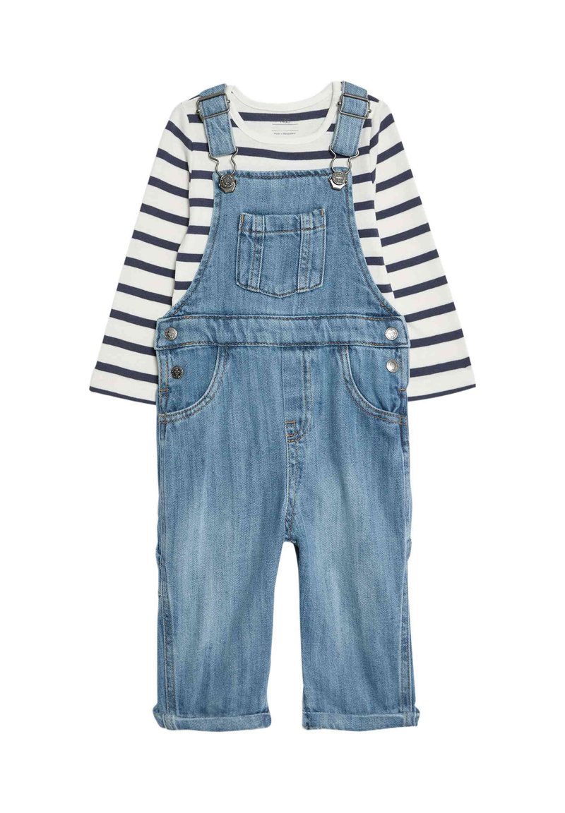 Pantalones de mezclilla en azul claro con tirantes ajustables, herrajes plateados y un bolsillo en el pecho, combinados con una camiseta de rayas azul marino y blanca de manga larga.