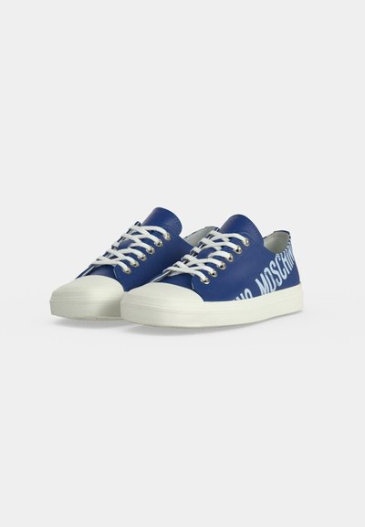 Baskets basses bleues avec des lacets blancs, des semelles blanches épaisses et "MOSCHINO" imprimé en grosses lettres blanches sur le côté.