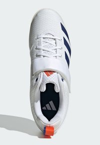 White athletic shoe with a textured mesh upper, navy stripes, a strap, and a brightly colored heel tab. Features a dark insole with logo.