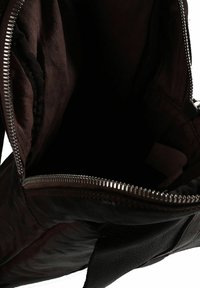 Borsa a tracolla in pelle marrone con chiusura con cerniera e finitura testurizzata. L'interno presenta una fodera in tessuto scuro e nessuna tasca visibile.