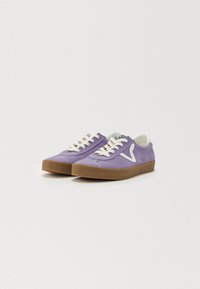 Lila vászon sneaker fehér fűzőkkel és logóval, barna gumitalppal, kerek orral és textúrált anyaggal a jobb tapadás érdekében.