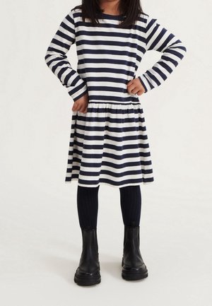 Stripet kjole med lange ærmer, mørkeblå og hvide striber, indsnævret talje, kombineret med ribstrikkede mørkeblå leggings og sorte ankelstøvler.