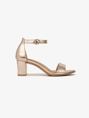 Sandales à talons d'or pâle avec une finition métallique, bout ouvert, une seule sangle sur le pied, sangle à la cheville avec une boucle et talon carré.