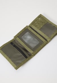 Portefeuille en tissu vert avec un compartiment zippé, une fenêtre pour pièce d'identité transparente et plusieurs emplacements pour cartes avec un design texturé.