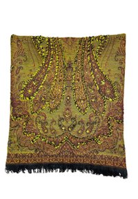 Coussin en textile avec des motifs complexes dans des nuances de jaune, brun et vert. Présente des bords à franges et des accents décoratifs en relief.