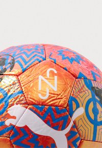 Fotbal Puma s oranžovými, modrými a bílými hexagonálními panely. Obsahuje cikcakové vzory, bílé logo a lesklý, strukturovaný povrch.