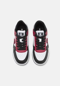 Zapatillas deportivas con un diseño de cuero negro, blanco y burdeos. Incluyen cordones, perforaciones y un logotipo en el lateral.