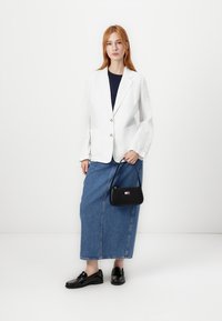 Valge linane bleiser, tumesinine topp, denimi maksihame, mustad loafersid ja väike must käsiraamat värvilise logodetailiga.