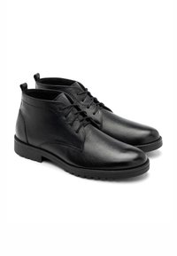 Czarne skórzane botki za kostkę z fakturowanym wykończeniem, sznurowanym wzorem, zaokrąglonym noskiem oraz solidną gumową podeszwą. Oferują pętelki z tyłu dla łatwego zakładania.