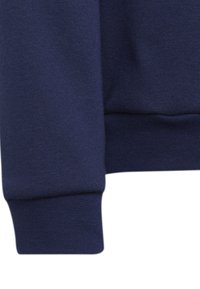 Sudadera azul marino con tejido que presenta un puño acanalado de textura suave y detalles de costura mínimos, principalmente en un color sólido.