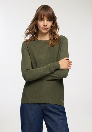 Maglione verde a maglia con collo rotondo e maniche lunghe, caratterizzato da una trama testurizzata, indossato su jeans in denim blu scuro.