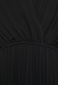 Abito nero con texture arricciata, caratterizzato da una vita aderente e un tessuto fluente. Materiale morbido e leggero con dettagli drappeggiati.