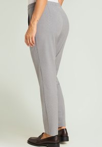 Grijze op maat gemaakte broek met een aansluitende pasvorm, voorzien van een subtiel patroon van kleine lichtgekleurde stippen en een gladde stoftextuur.