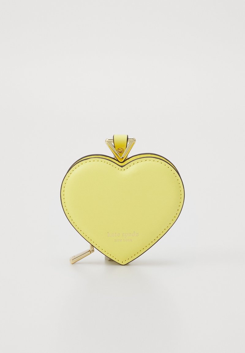 Gul hjerteformet skinnpung med gullglidelås, svart søm og et trekantet metallbeslag med "kate spade"-merke.