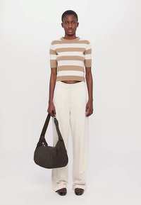 Striped beige and white cropped sweater, loose white trousers, and dark shoulder bag with a flat bottom, worn with black shoes.