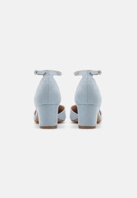 Light blue suede high-heeled shoes with a rounded toe, ankle strap, and block heel. Notable back design with a cutout and buckle.
