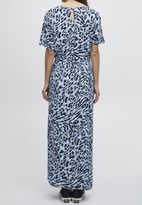 Maxiklänning i ljusblått med svart djurmönster. Har korta ärmar och en nyckelhålsdetalj i ryggen. Bärs med svarta sneakers.