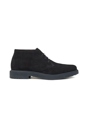 Stivali alla caviglia in suede nero con punta rotonda, chiusura con lacci e suola in gomma texturizzata. Presentano un design semplice e lineare.