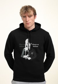 Felpa nera con cappuccio caratterizzata da un'immagine di un personaggio dai lunghi capelli chiari e un'espressione seria, che tiene un libro, con il testo "Una volta Addams, sempre Addams."