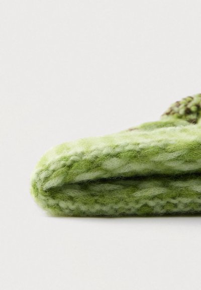 Pătură verde tricotată, realizată dintr-un material moale și texturat, având nuanțe diferite de verde și un model gros, robust.