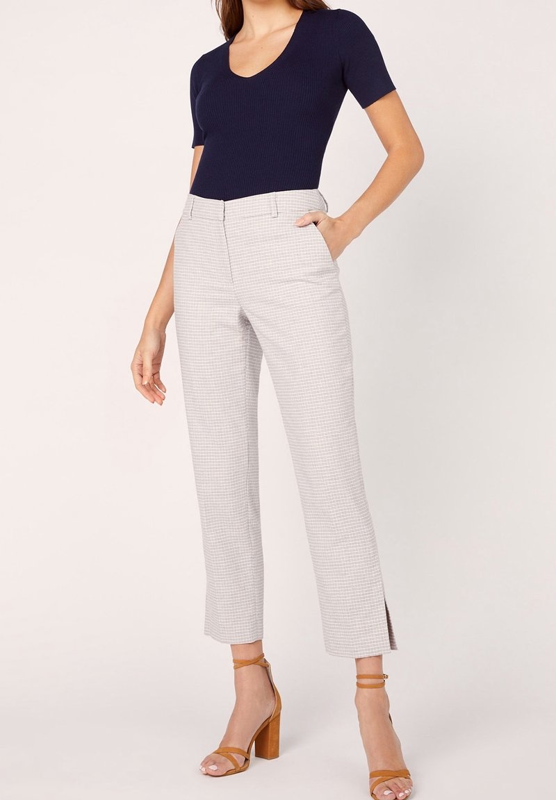 Navy ribbed short-sleeve top paired with light gray checked high-waisted trousers featuring side slits and brown strap high-heeled sandals.