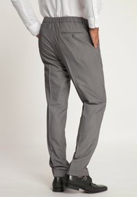 Pantaloni grigi con una texture sottile, cintura elasticizzata, tasche laterali e posteriori, abbinati a scarpe in pelle nere.