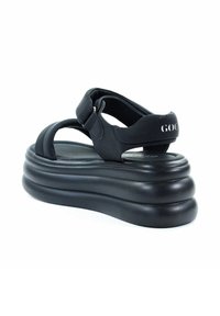 Czarne sandały na platformie z grubą, formowaną podeszwą i regulowanym paskiem. Miękki materiał o gładkiej strukturze i minimalistycznym designie.