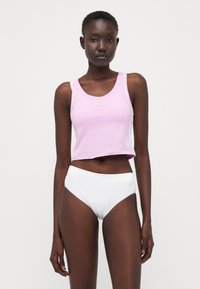 Lys rosa, kort tanktop med rund hals og hvit logo, kombinert med høyhalsede hvite truser, glatt stoff, tettsittende design.