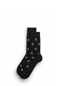 Sorte sokker dekoreret med små peberkager iført nissehuer, arrangeret side om side på en hvid baggrund.