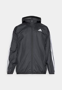 Sort letvægtsjakke med lynlås, hætte og hvide side-striber. Fremstillet af glat, vandafvisende materiale med et minimalistisk design.