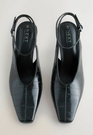 Black patent leather slingback shoes with a pointed toe, featuring a textured finish and a thin adjustable ankle strap.