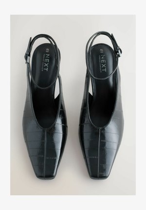 Fekete lakkozott bőr szandálcipő, hegyes orral, texturált felülettel és vékony, állítható bokapánttal.