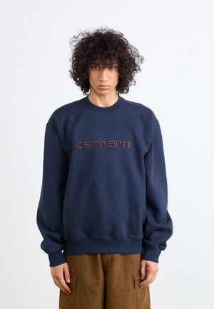 Sudadera azul marino con cuello redondo, que presenta un logotipo "carhartt" bordado en marrón centrado en el pecho, hecha de una tela texturizada.