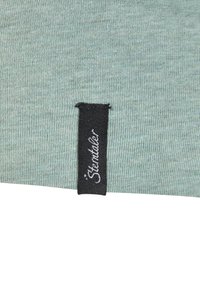 Hellgrüner Stoff mit feiner Rippenstruktur, versehen mit einem schwarzen Etikett mit weißem Text, das an der Seite angenäht ist.