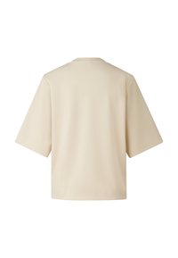 Béžové tričko s krátkým rukávem a kulatým výstřihem, s volným střihem a hladkou texturou. Bez viditelných vzorů nebo designových prvků.