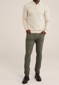 Cream textured long-sleeve polo shirt with three buttons, paired with olive green slim-fit trousers and black dress shoes.