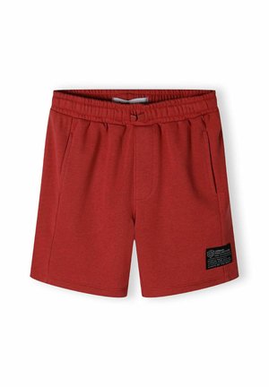 Red athletic shorts made from soft material, featuring an elastic waistband, side pockets, and a stitched label with black accents.