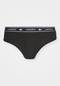 Czarne kostiumy kąpielowe z miękkiego materiału, z szerokim elastycznym pasem w biały logo "Lacoste" oraz emblematem krokodyla.