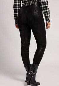 Leggings de cuero sintético negro con una textura suave, diseño ajustado y cinturilla alta. Combinados con botas de tobillo negras con estampado de cocodrilo.