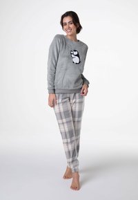 Felpa grigia in pile con applicazione a forma di pinguino; abbinata a pantaloni pigiama a quadri grigio chiaro. Texture morbida, vestibilità rilassata, bordi a costine.