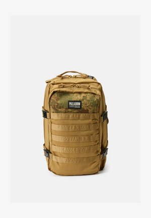 Tansfarbene Tasche mit Camouflage-Panel, mehreren Reißverschlusstaschen, vorderem Gurtband zur Befestigung, robusten Griffen und verstellbaren Trägern.