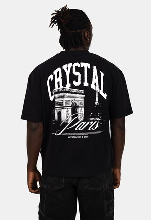 Schwarzes Baumwoll-T-Shirt mit einem großen weißen Grafikdesign des Arc de Triomphe und des Eiffelturms, mit "CRYSTAL Paris" in fetter Schrift.