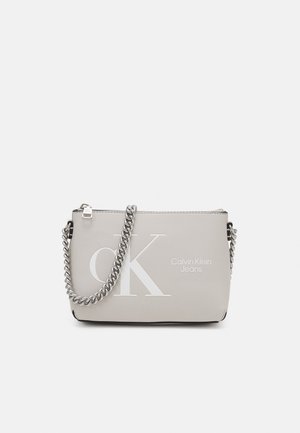 Calvin Klein Jeans Schultertasche in Hellgrau, mit glatter Textur, silberner Kettenriemen und auffälligem weißen Logo auf der Vorderseite.