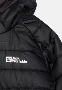 Giacca a vento nera con cuciture orizzontali, cappuccio e logo bianco "Jack Wolfskin". Il materiale sembra liscio con una leggera lucentezza.