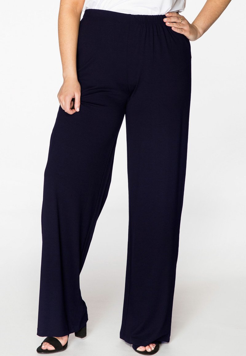 Maritieme wijde broek met een elastische tailleband, gemaakt van zachte stof. Kenmerkt zich door een gladde textuur en een losse pasvorm, gedragen met zwarte haksandalen.